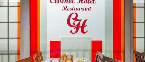 Mesa de desayuno dispuesta con diferentes platos y bebidas, un logotipo y una paleta de colores rojo y blanco.