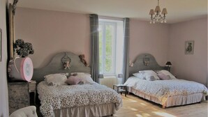 Une chambre avec deux lits, une chaise, une commode et une fenêtre avec des rideaux.