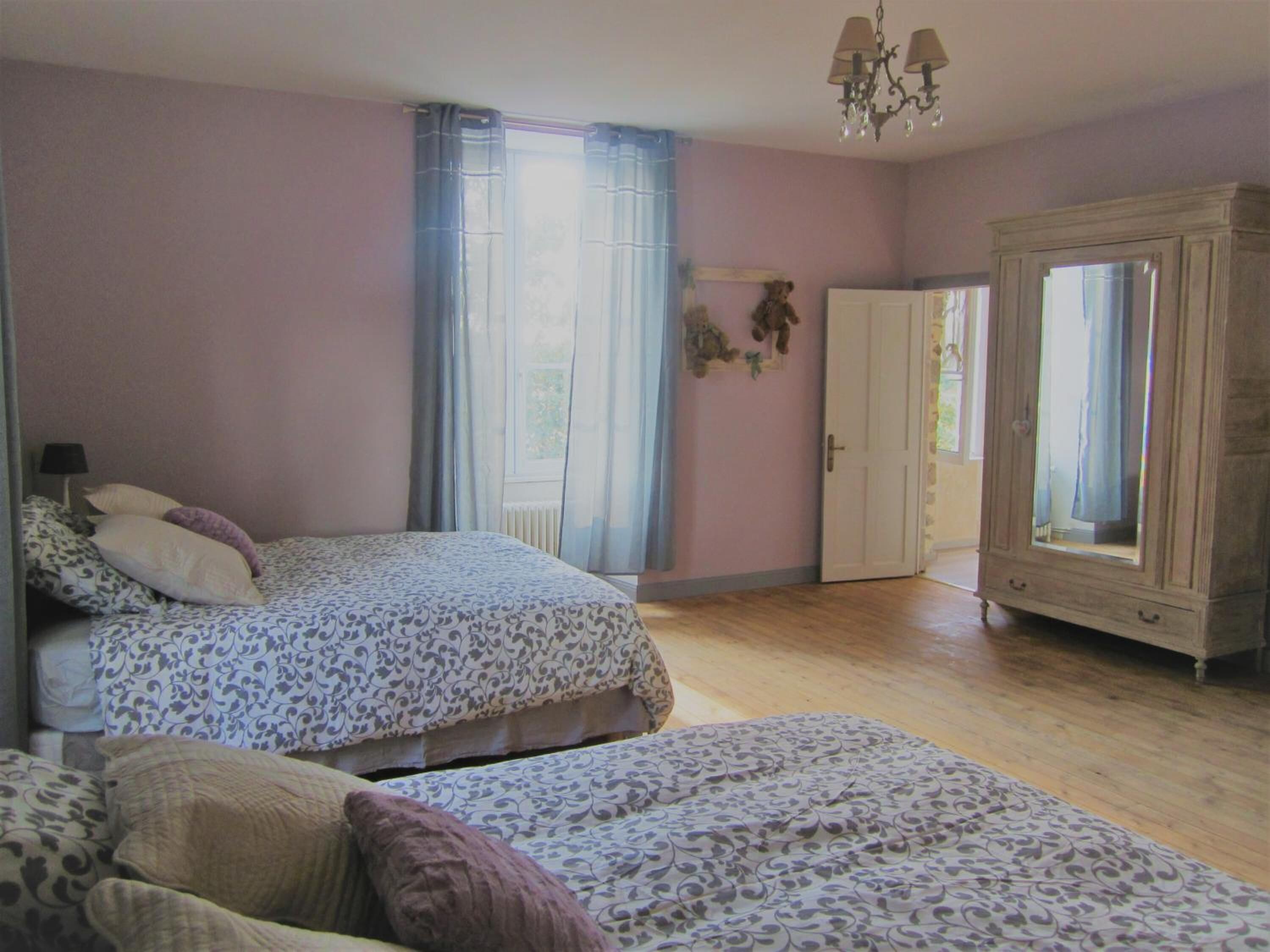 Une chambre avec deux lits, une armoire et un lustre.