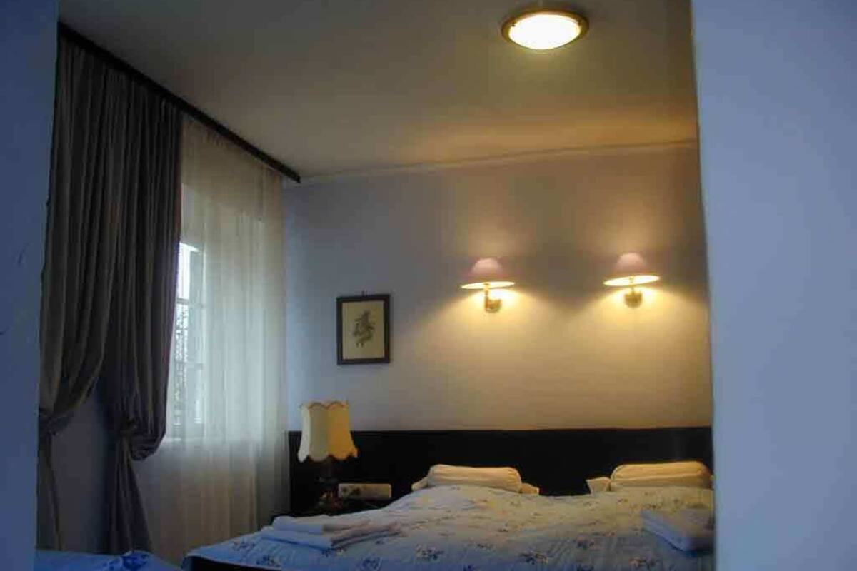 Ein Hotelzimmer mit einem Bett, einem Nachttisch, einer Lampe und einer Wandleuchte.