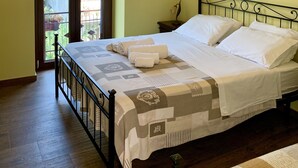 Een keurig opgemaakt bed met witte lakens, een kroonluchter en een klein nachtkastje met een lamp.