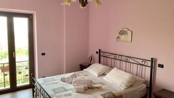 Ein Schlafzimmer mit Bett, Nachttisch, Wandlampe und Balkontür.