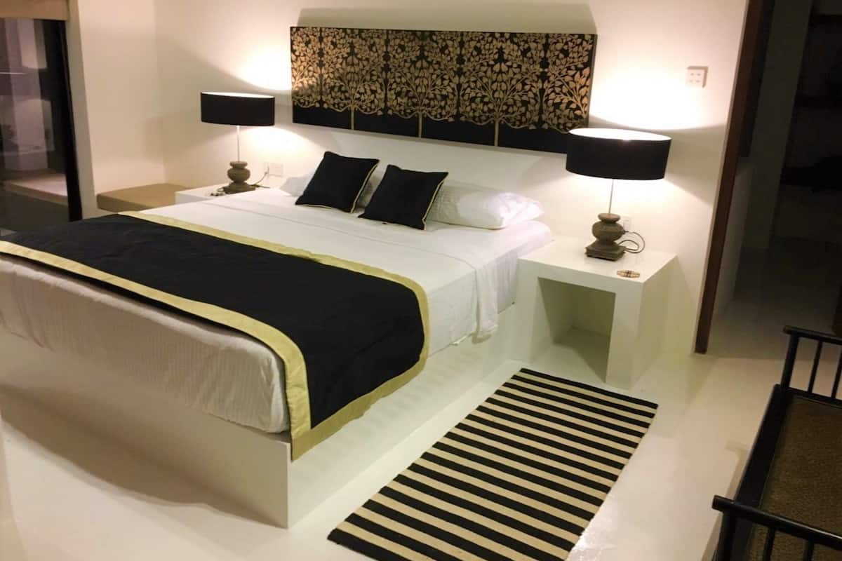 A modern hotel room with a large bed, two bedside tables, and a decorative wall panel.
