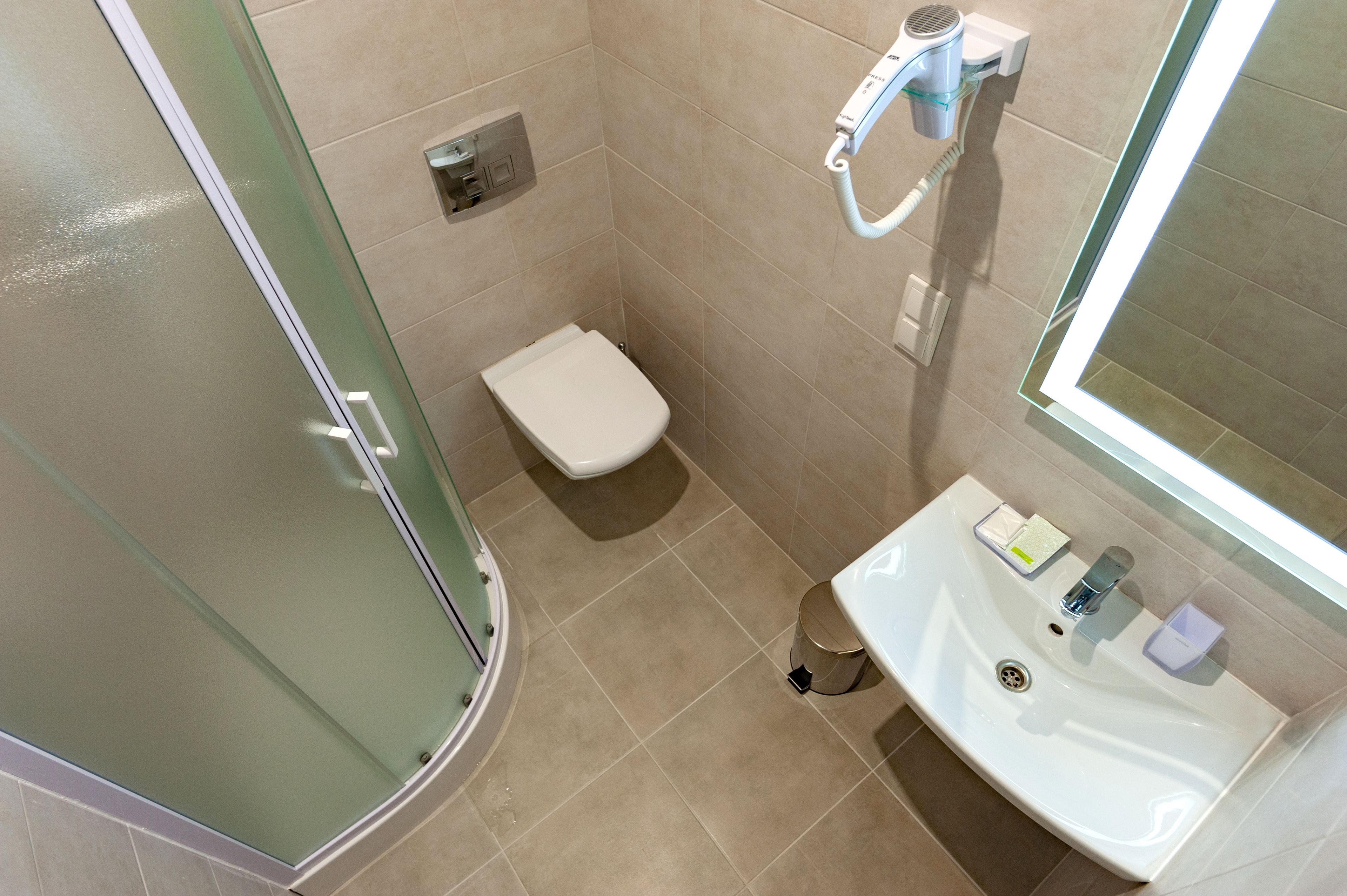 Un baño con cabina de ducha de vidrio, inodoro blanco y lavabo con espejo.