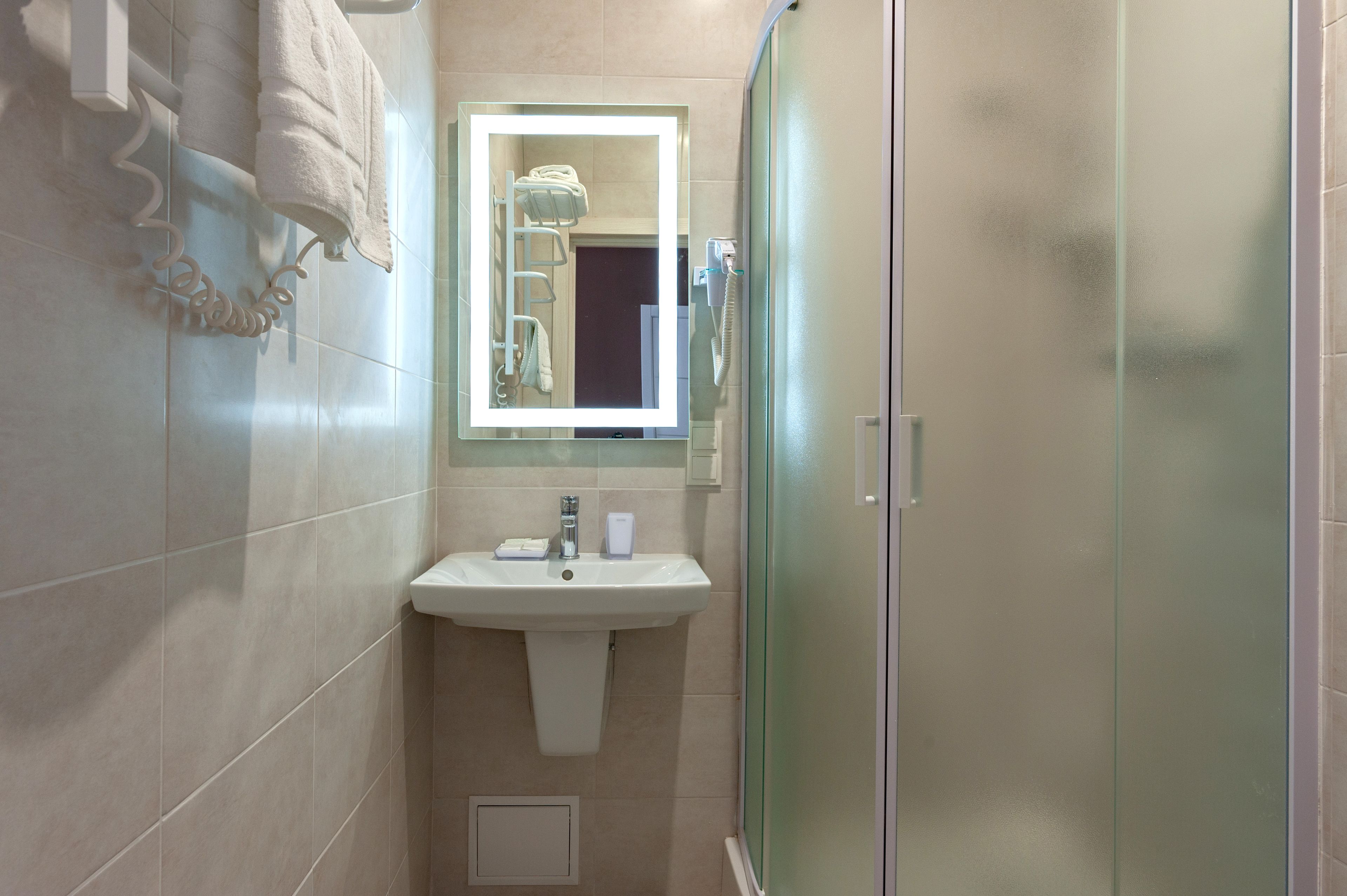 A bathroom with a sink, mirror, towel rack, and glass shower enclosure.