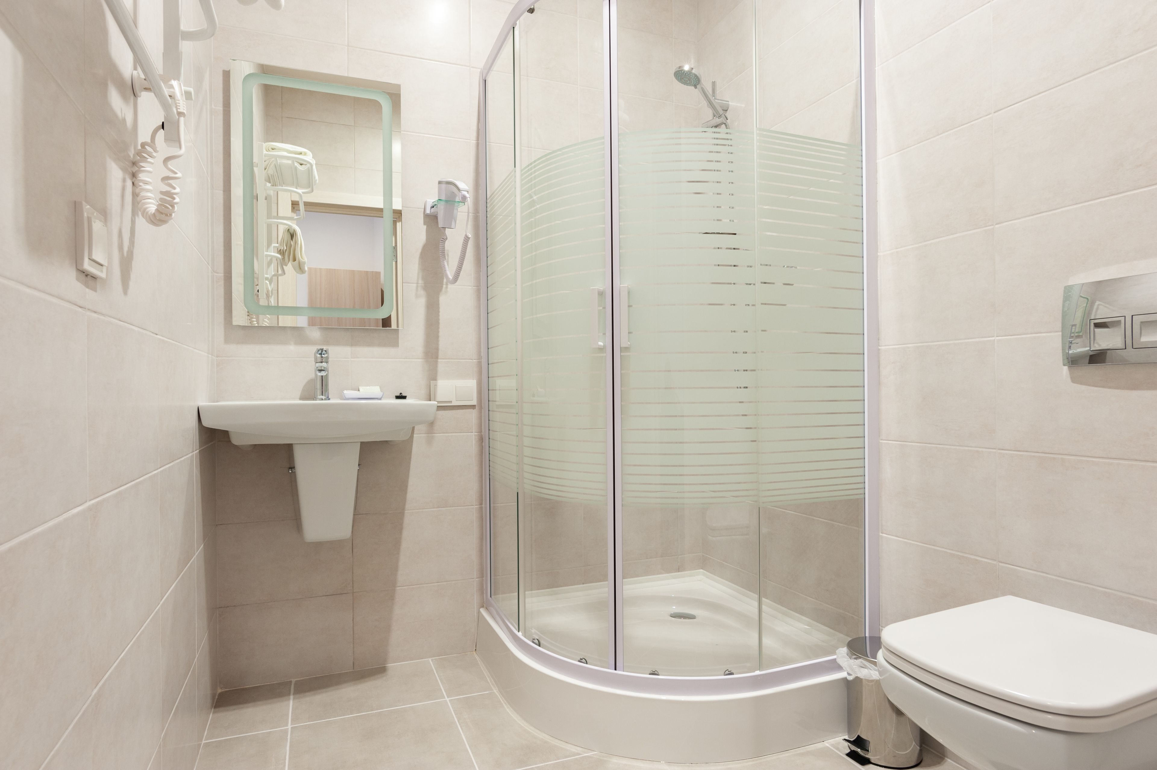 A modern bathroom with a glass-enclosed shower, a white sink, and a toilet.