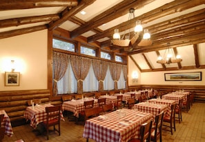 Ein Restaurant mit Holzbalken, karierten Tischdecken und einer Chandelüster.