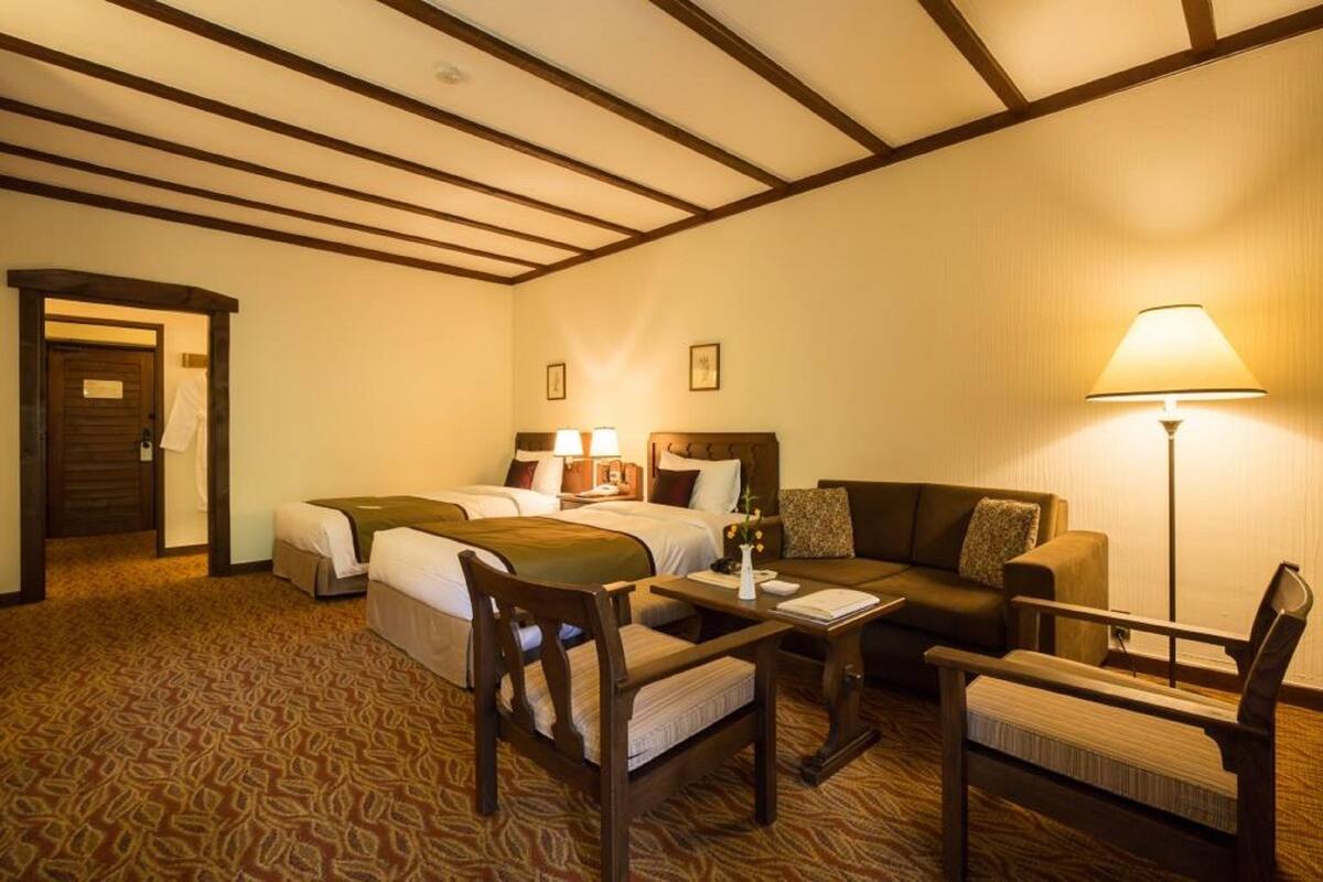 Een hotelkamer met een bed, twee nachtkastjes met lampen, een bank, een fauteuil en een vloerbedekking.
