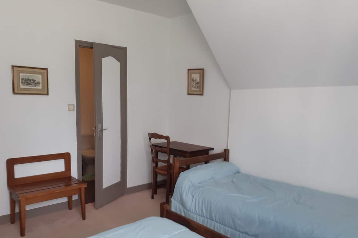 Een slaapkamer met een bed, een bureau, een stoel en een bankje.