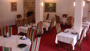 A dining area with striped chairs and tables, a fireplace, and paintings on the walls. - Auberge de Pen Mur (Muzillac)