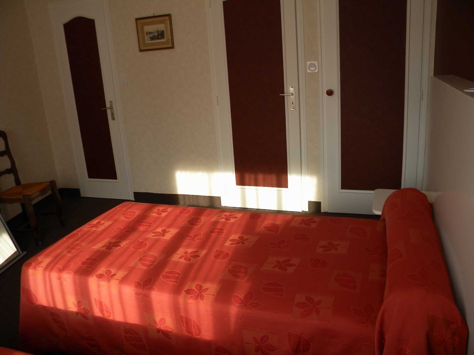 A room with a bed, a chair, and a wardrobe with a mirror.