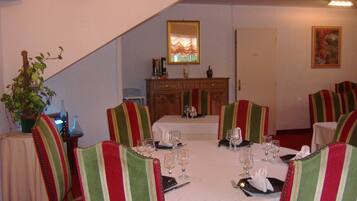 Une salle à manger avec un plafond haut, un lustre et une table à manger dressée pour six personnes.