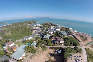 An aerial view of a coastal residential area with houses, some with green roofs, and a clear view of the sea. - 2 Bed Seaview Villa A2 SDV202-By Samui Dream Villas (Koh Samui)