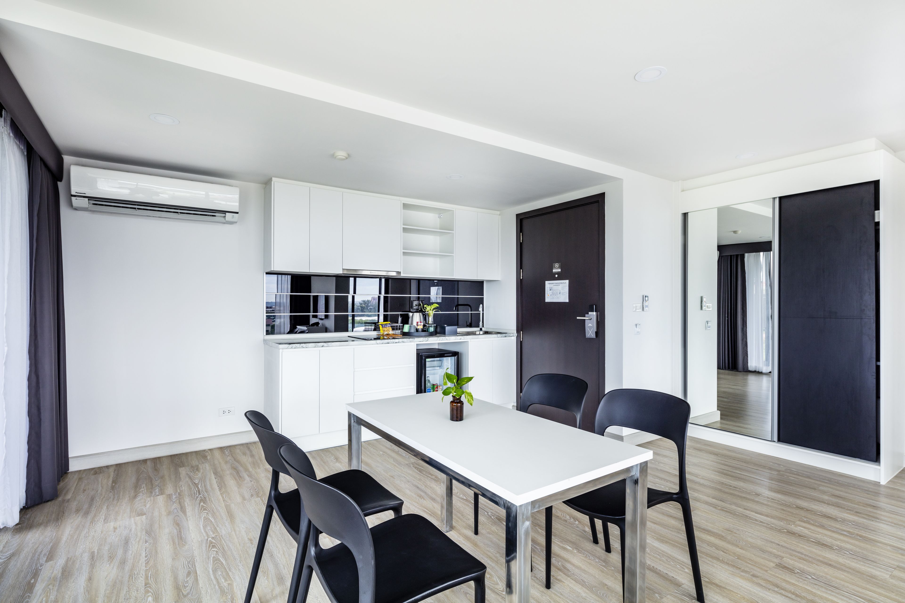 A modern kitchen with white cabinets, a black countertop, and a dining area with a white table and black chairs.