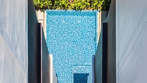 Un edificio moderno con una pared de mosaico azul y un estrecho pasaje.