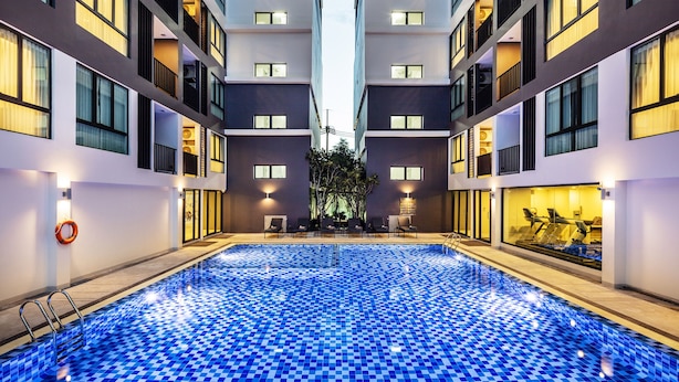 Un hotel moderno con piscina central, varios balcones y zona de gimnasio.