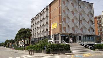 Un hotel moderno con una facciata geometrica distintiva, un ingresso ben visibile e una scala che conduce all'ingresso.