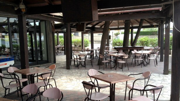 An outdoor café with tables and chairs arranged under a wooden pergola. - Hotel Quadrifoglio (Comacchio)