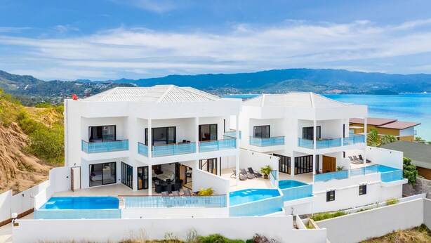 Un edificio moderno de varios pisos con piscina, balcones y vistas al mar.