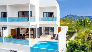Un moderno edificio de dos pisos con piscina, balcones y vistas a las montañas.