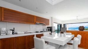 Una cocina moderna con encimeras blancas, armarios de madera y una isla grande con asientos.