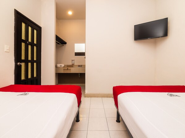 A hotel room with two beds, a TV, a bathroom with a mirror, and a red bedspread. - Hotel Río Puebla Centro (Puebla)