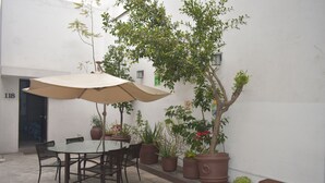 An outdoor patio with a table and chairs, surrounded by potted plants and a large umbrella. - Hotel Río Puebla Centro (Puebla)