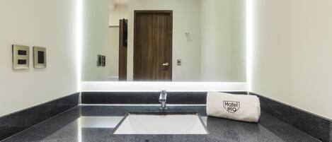 Un baño con un espejo grande, un lavamanos y una toalla con un logotipo.