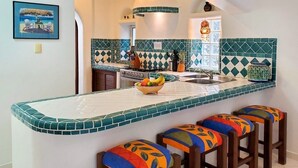 A kitchen with a central island, colorful stools, and a decorative backsplash. - Natz Ti Ha H101 by PRP (Playa del Carmen)