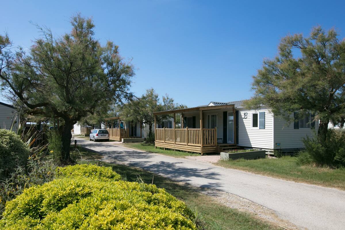 Une rangée de maisons mobiles dotées de terrasses en bois et d’une allée en gravier.