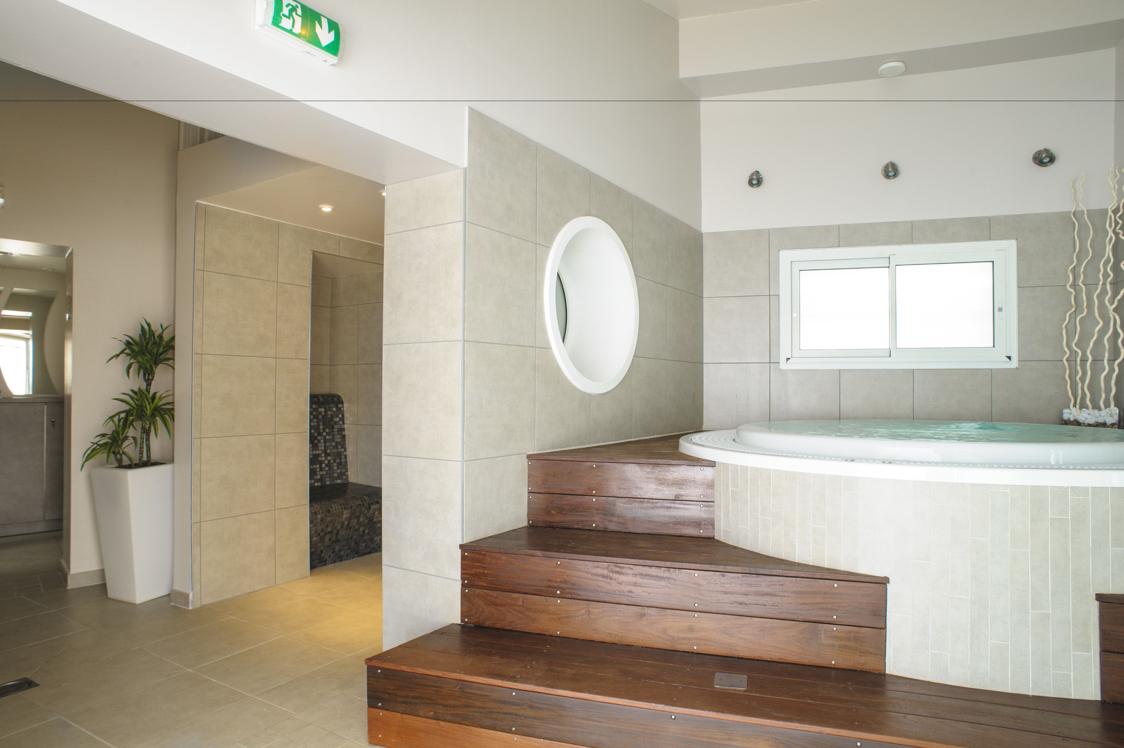 A modern bathroom with a wooden staircase, a large mirror, and a bathtub.