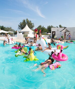 A swimming pool with people using various inflatable toys. - Camping Le Clos du Rhône (Saintes-Maries-de-la-Mer)