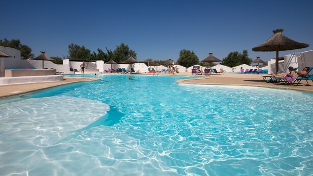 A clear swimming pool with lounge chairs and umbrellas around it. - Camping Le Clos du Rhône (Saintes-Maries-de-la-Mer)