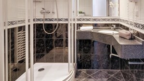 Un baño moderno con cabina de ducha de vidrio, tocador con lavamanos y espejo.
