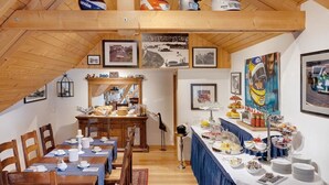Un comedor con mesas y sillas de madera, una barra de buffet y varias imágenes enmarcadas en las paredes.