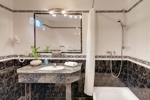 Un baño con lavamanos de mármol, un espejo, una ducha y un perchero para toallas.