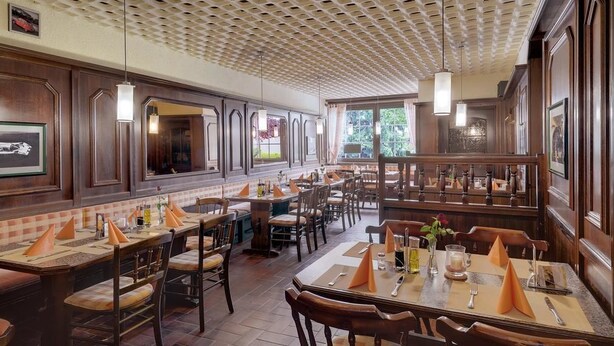 Un restaurante con paneles de madera, manteles a cuadros y servilletas anaranjadas.