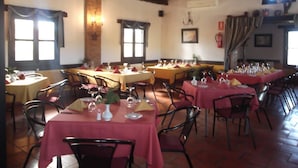 Un restaurante con varias mesas dispuestas para comer, que presenta un interior rústico con vigas de madera y suelos de baldosas.