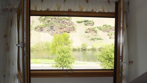 A room with a large window, curtains, a radiator, and a bed. - Weingut & Gästehaus Kaufmann-Schneider (Erden)