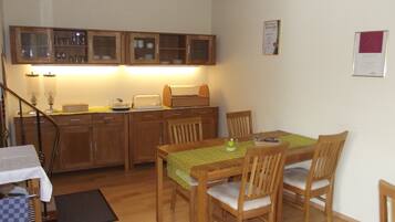 A compact kitchen with wooden cabinets, a dining table with chairs, and a small countertop with a toaster.