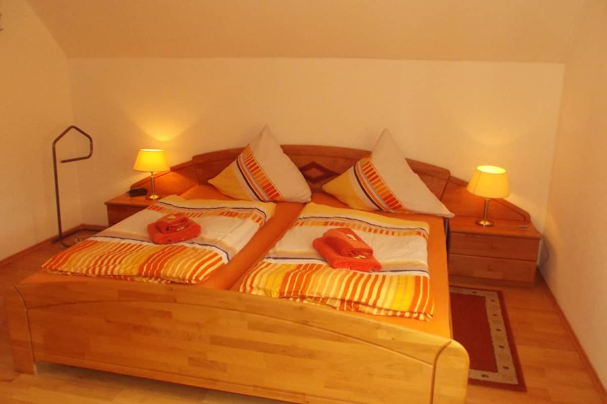 Une chambre confortable avec un lit en bois, une literie à rayures et deux lampes de chevet.