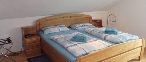 A single bed with a wooden headboard, a bedside table, and a small nightstand.