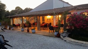 An outdoor dining area with tables and chairs, surrounded by potted plants and a gravel path. - Les Chênes Verts (Saint-Savinien)