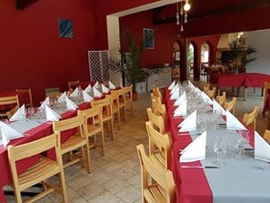 A dining area with wooden chairs and tables, each set with white napkins and glasses. - Les Chênes Verts (Saint-Savinien)