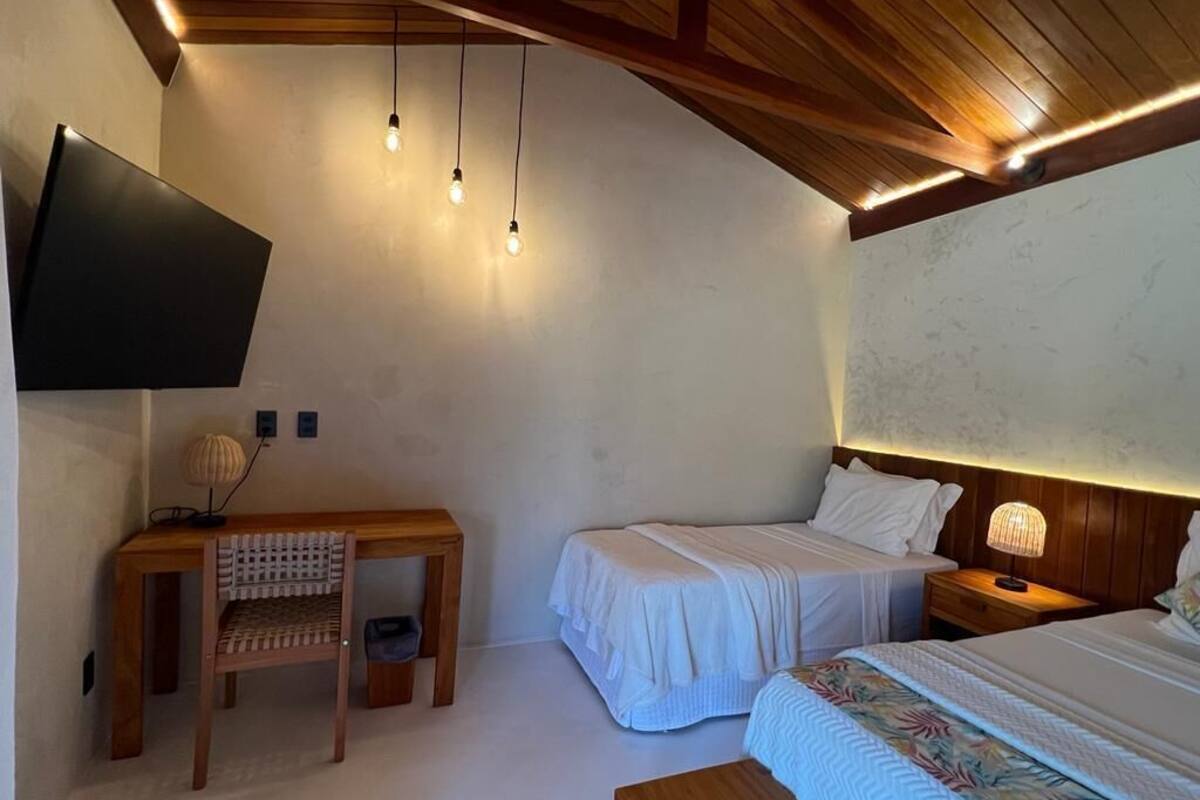 A bedroom with a bed, bedside tables, a desk, and a TV mounted on the wall.