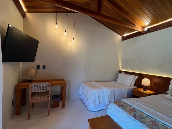 Une chambre à coucher comprenant un lit, des tables de chevet, un bureau et un téléviseur fixé au mur.