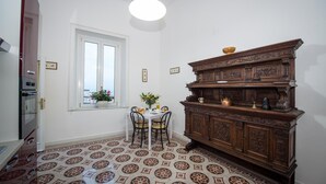 A dining area with a patterned floor, a wooden cabinet, a window with a view, and a table with chairs.