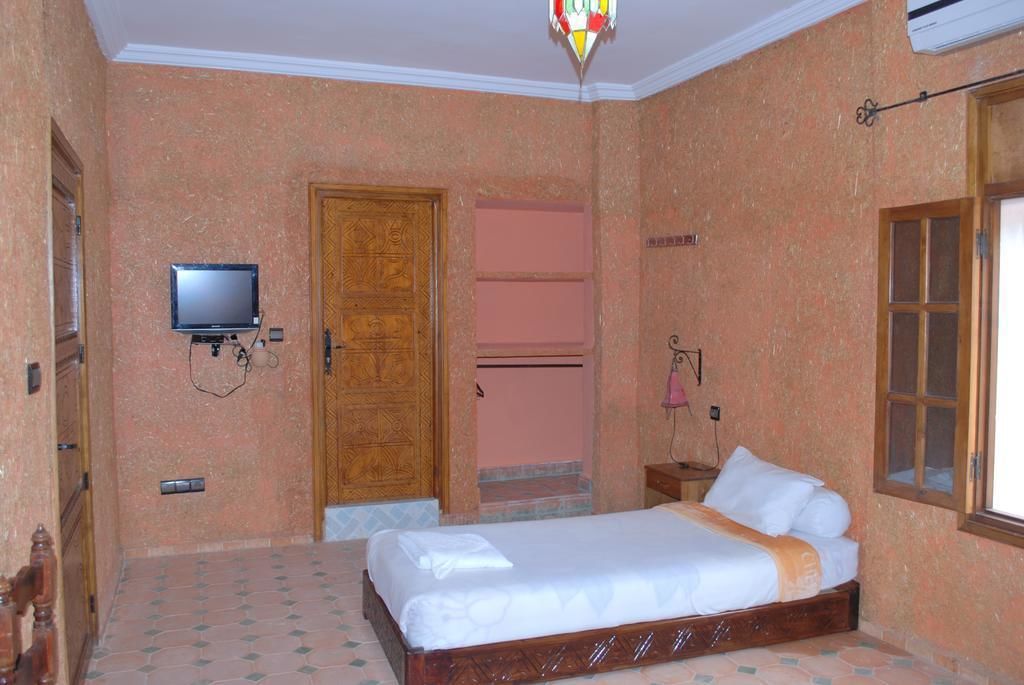A bedroom with a bed, a television, a wardrobe, and a window.