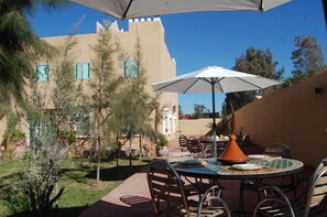 An outdoor dining area with a table, chairs, and an umbrella. - Gite Souss (Issen)