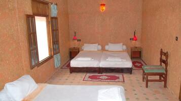 A room with two beds, a window, a wall-mounted lamp, and a chair.